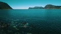 Flight over the rocky coast. Clear, azure water and sunny weather. The sea and mountains in the background. Norway 2020.