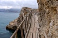 Flimsy old rotten bridge across the rocks on the sea coast Royalty Free Stock Photo