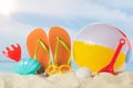 Flip flops with beach ball and toys in sand on blue Royalty Free Stock Photo