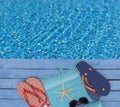 Flip-flops, beach towels and sunglasses by the swimming pool Royalty Free Stock Photo