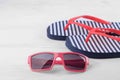 Flip flops in blue and white stripes with red sunglasses. Beach accessories. Royalty Free Stock Photo