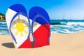 Flip flops with Filipino flag on the beach. Philippines resorts, vacation, tours, travel packages concept. 3D rendering