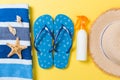 Flip flops, straw hat, starfish, sunscreen bottle, body lotion spray on yellow background top view . flat lay summer beach sea