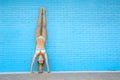 Flip your world upside down. Portrait of an attractive young woman doing a handstand against a blue brick wall. Royalty Free Stock Photo