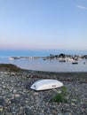 Flipped boat on the rocky shore against the background of the coast with vessels. Rye Harbor Beach. Royalty Free Stock Photo