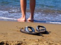 Flippers on sand and men feet in water on beach Royalty Free Stock Photo