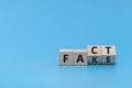 Flipping FAKE to FACT word on wooden cube block on blue background Royalty Free Stock Photo