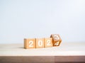 Flipping the 2023 to 2024 year calendar numbers on wooden cube blocks isolated on wood table.