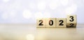 Flipping of wooden block cube to change 2022 to 2023 with bokeh for merry Christmas and happy new year preparation concept
