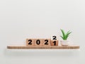 Flipping wooden cube block for change 2021 to 2022 on wooden shelf and plant for preparation merry Christmas and happy new year,