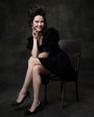 Portrait of young happy woman in image of medieval royal person in black dress isolated on dark vintage background.