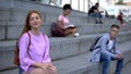 Flirting beautiful teen female sitting near student smiling to girl, sympathy