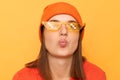 Flirting funny woman wearing orange jumper and glasses in minecraft style isolated over yellow background keeps lips pout sending