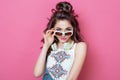 Flirting Pretty fashion cool girl with headphones wearing colorful clothes white sunglasses with curly hair looks isolated over pi