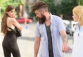 Flirting in the street. Love triangle and threesome. Man cheating his girlfriend. Bearded man looking at other girl Royalty Free Stock Photo