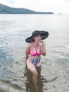 A flirty asian woman giggles while taking a dip at the beach