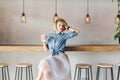 Flirty blond girl with blue eyes and bright pink lips sitting in a coffee shop on a chair drinking coffee and playing Royalty Free Stock Photo