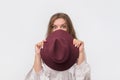 Flirty funky caucasian woman hiding behind fashionable trendy head wear, with wide open eyes. Royalty Free Stock Photo