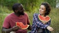 Flirty mixed couple discussing plans for future, eating delicious watermelon