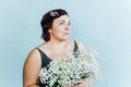 Flirty overweight confident woman in dress with a bouquet of gypsophila.