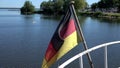 Flittering black-red-golden flag of the state of Germany at the stern of a pleasure boat