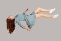 Floating in air. Relaxed girl in vintage ruffle dress levitating keeping eyes closed, sleeping while flying mid-air