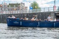 Floating Amsterdam blue canal boat diner cruise with tourists enjoying sites of city while wining and dining