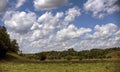 Floating in the blue sky, large clouds over the meadow. Royalty Free Stock Photo