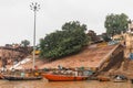 Floating boats and diversity of Indian people living at the ghat with old buildings on background along the Ganges Ganga river