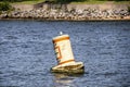 Floating bouy in lake saying Keep Right bobbing on rough water with relfection and blurred shore and rip rap in distance Royalty Free Stock Photo