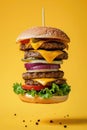 Floating Cheeseburger with Multiple Patties Against Yellow Background Royalty Free Stock Photo
