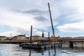 Floating construction barge with a crane on the harbour against cityscape of Stockholm Royalty Free Stock Photo