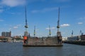 Floating dock with four cranes where ships are repaired in the industrial cargo port of Hamburg, city in the background, blue sky Royalty Free Stock Photo