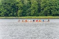 Floating eight rowing boat with tourists and instructor in the waters of Galve lake surrounded by green summer forest