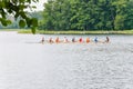 Floating eight rowing boat with tourists and instructor in the waters of Galve lake surrounded by green summer forest