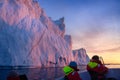 Floating glaciers in the rays of the setting sun with a boat with photographers