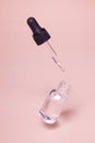 Floating glass dropper bottle with serum or oil and a flying pipette. Skin care minimalist concept mock up