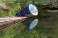 Metal barrel float in wetland lake, reflection on a water surface