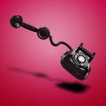 Floating Old black telephone with shadow against red gradient background