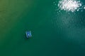 Floating platform with a sun tanning couple aerial top view. Bright sn reflecting in green lake waves. Peruca Lake, Dalmatia,