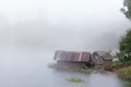 Floating raft house on river with foggy background.