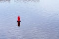 Floating red navigational buoy on blue water of Dnipro River. Buoy in the river. Navigation equipment. Royalty Free Stock Photo