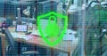 Floating shield icon displaying padlock hovering over office desk with professionals using laptops Royalty Free Stock Photo