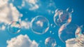 Floating soap bubbles against a bright blue sky with scattered white clouds Royalty Free Stock Photo