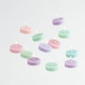 Floating tea light candles in assorted pastel colors on a solid white background Royalty Free Stock Photo