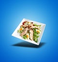 Floating White plate with Caesar salad on blue gradient