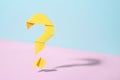 Floating yellow origami question mark on bicolor background