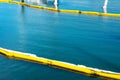 Floating yellow and white oil containment boom on calm water. Pollution concept . A containment boom is a temporary floating Royalty Free Stock Photo