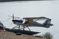 Floatplane or seaplane with two slender floats mounted under the fuselage to provide buoyancy is parked on the lake front,