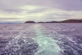 Floats the boat behind him a beautiful plume of water and bubbles on the horizon you can see the island. Royalty Free Stock Photo